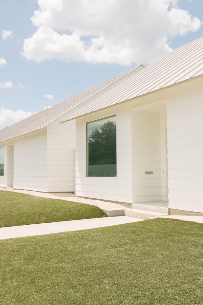 Mastering the First Impression: Your intriguing post title goes here A modern white house in Houston with large glass windows and a sleek design, under a clear blue sky.
